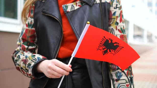 Unrecognizable woman holding Albanian flag. Girl walking down street with national flag of Albania