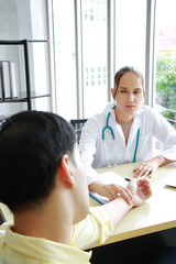 Obraz premium Caucasian Female Psychiatrist or neurologist is counseling and touching pulsation of patient for treatment asian man in clinic at hospital. Major depressive disorder patients and healthcare Concept.
