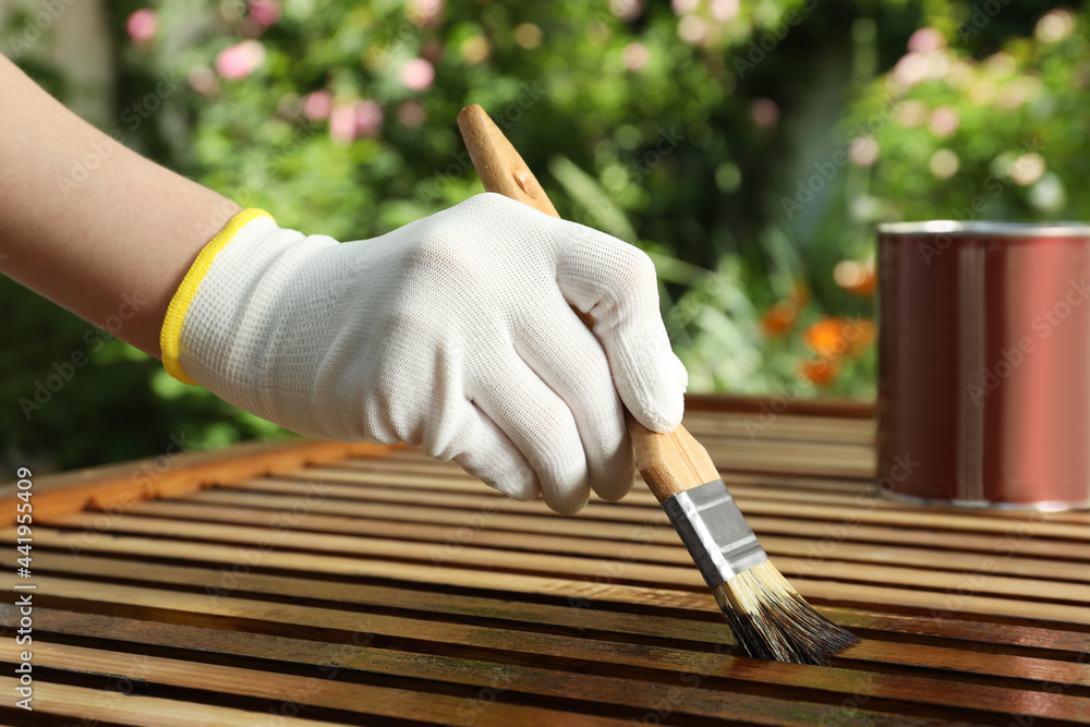 Poster Woman applying wood stain onto planks outdoors, closeup