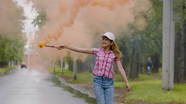 Child schoolgirl waving torches with colored smoke