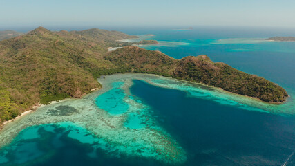 aerial view tropical island Bulalacao with blue lagoon, coral reef and sandy beach. Palawan, Philippines. Islands of the Malayan archipelago with turquoise lagoons.