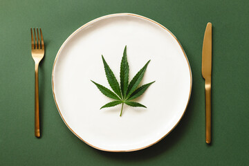 Leaf of cannabis on white plate with golden rim.