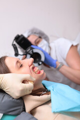 The dentist takes pictures of the patient's teeth. Malocclusion. Orthodontist work. Frach is out of focus. Vertical photo.