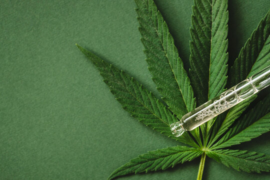 Pipette with cannabis extract on green background.
