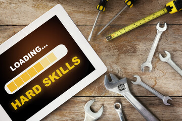 Hard skills loading on computer digital tablet with tools supplies on wooden background. Expertise challenge concept and business success idea