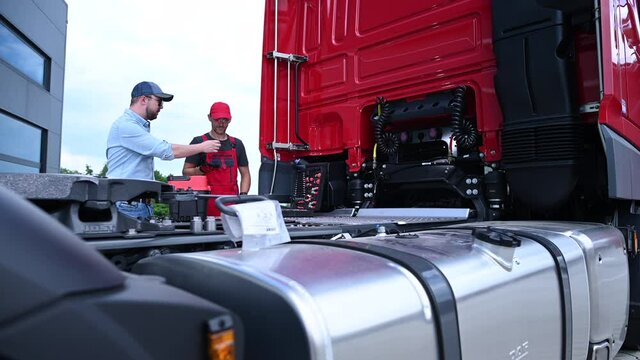 Caucasian Truck Mechanic and Driver Discussing Some issues with the Vehicle