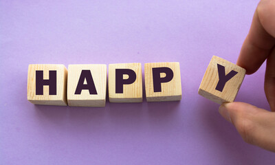 Wooden cubes with word HAPPY. Wooden cubes on a pink background.