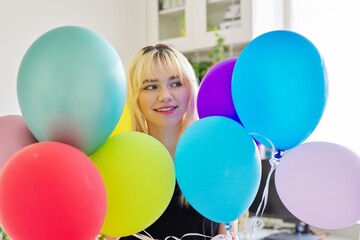 Fototapeta na wymiar Close up of colored balloons and happy smiling face of blonde teen female
