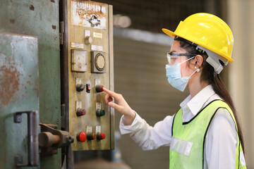 Portrait of woman Asian mechanic engineer worker wearing safety equipment beside the switch of...