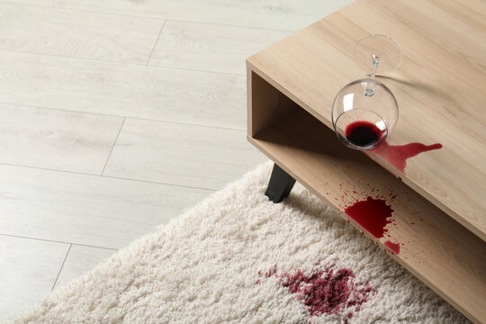 Overturned glass and spilled red wine on white carpet indoors, space for text