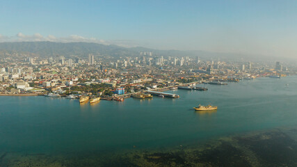 Panorama of Cebu City, seaport with ships and ferries and modern skyscrapers and residential buildings. Philippines.