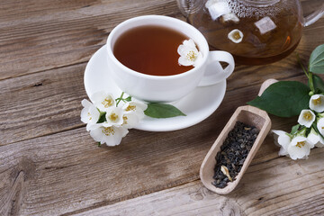 Green tea with jasmine in cup and teapot on wooden rustic table