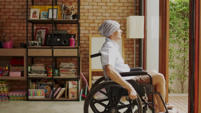 Old senior Asian man sitting in wheel chair in nusing home looking out of window and thinking. Lonely elderly  man spending day alone at home. Concept of family life insurance.