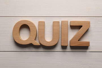 Word Quiz made with wooden letters on white table, flat lay