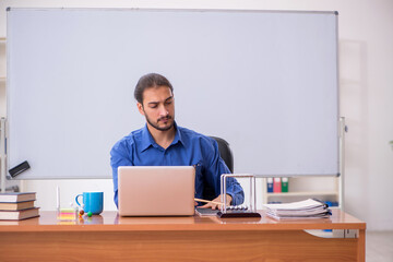 Young male teacher physicist sitting in the classroom
