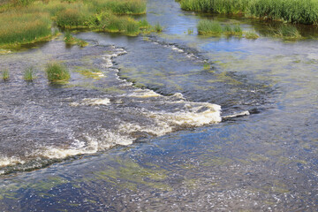 View of a shallow, wide river with miniature waterfalls