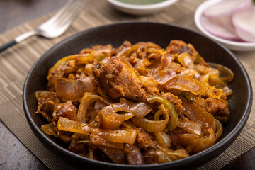 Chilli chicken is a popular Indo-Chinese dish, served on a plate on wooden background
