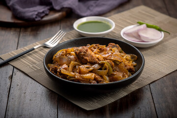 Chilli chicken is a popular Indo-Chinese dish, served on a plate on wooden background
