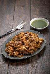 Chilli chicken is a popular Indo-Chinese dish, served on a plate on wooden background
