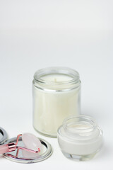 Closeup of a pampering skincare set – moisturizer, rose quartz roller, mirror and scented candle.