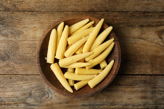 Fresh baby corn cobs on wooden table, top view