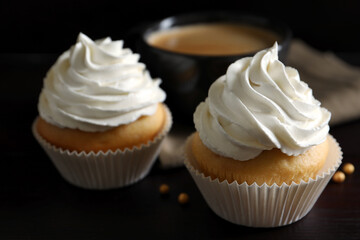 Delicious cupcakes with white cream on wooden table, closeup