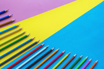 Colorful colored pencils on multicolored paper background. Free space for text