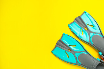 Pair of turquoise flippers on yellow background, flat lay. Space for text © New Africa