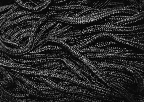 Unorganized bundle of black textured polyester braided rope, background, isolated, textured and pattern