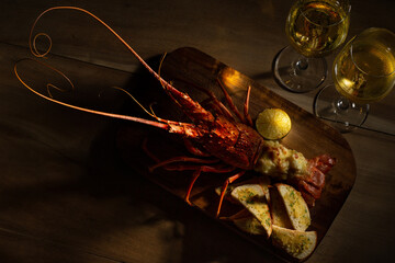 Red lobster with croutons and sauce and two glass of white wine on wooden surface with copy space