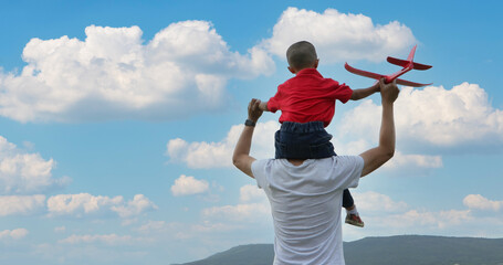 Father and son playing toy airplane on the Meadow at sunset with happy emotion. Family, Holiday and Travel concept.