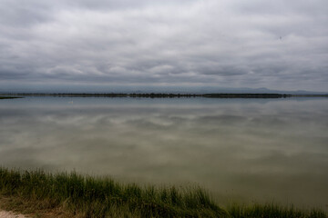 endless lake with green water and clouds reflected in it 