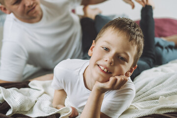 Father plays with his son 7-10 on bed. Dad tickles kids feet. Family, having fun