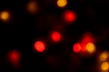 Defocused bokeh red big lights on black background. Blurred abstract red glitter wallpaper for love theme, Valentine's day.