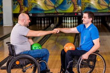 Two young disabled men in wheelchairs playing bowling in the club