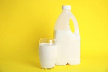 Gallon bottle and glass of milk on yellow background