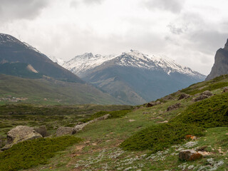 Fototapeta premium View of the green valley from the main attraction of the village of Eltyubyu, the City of the Dead. High snowy mountains are visible on the horizon. Kabardino-Balkaria, Russia