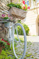 Fototapeta na wymiar Flowers and a white bicycle on a street corner. Detail. Close up. Vintage bike
