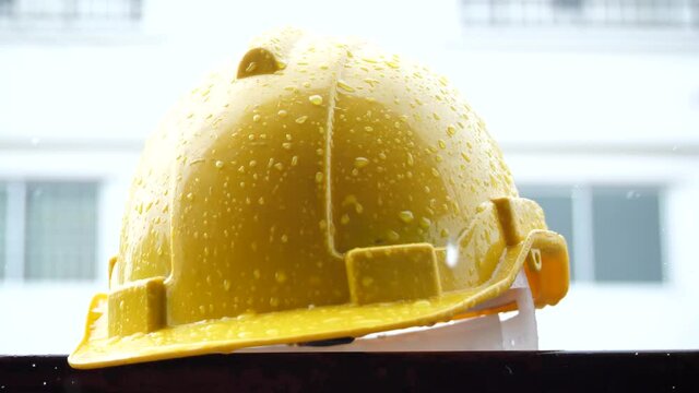 Construction site with rain concept, yellow helmet with heavy rain, rainstorm and construction