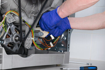 close-up of the installation of the new control unit of the washing machine mechanisms, by the...