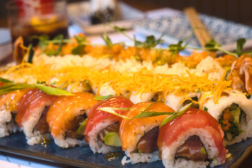 The variety of food showing the taste of Japan - mixed set of colorful seafood sushi, tuna, losos and shrimp nigiri, tempura and shrimp rolls
