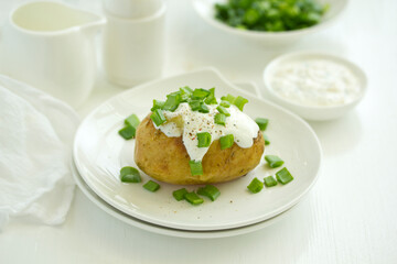 Baked potatoes with cheese, served with sour cream and onions. Selective focus