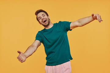 Happy young smiling man in casual clothing looking at camera and gesturing hug