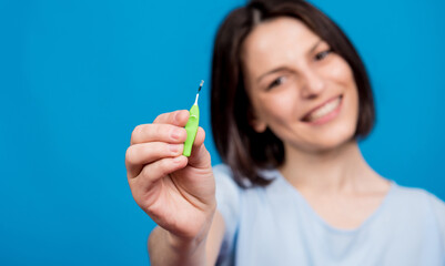 Beautiful happy young woman using interdental brush on blue background