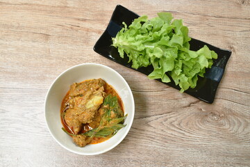 spicy stir fried pork bone with herb and curry in bowl eat couple vegetable on plate