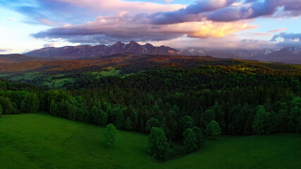 Colorful sunset in mountains, aerial view. Scenic sunset with colorful clouds above Tatra mountain range. Epic panoramic view of Tatras in Poland and Slovakia.