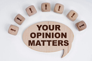 On a white background, cubes with an exclamation mark and a sign - thoughts with the inscription - YOUR OPINION MATTERS