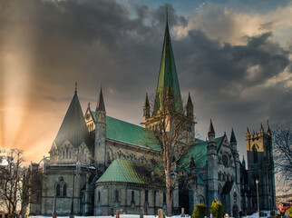 Fototapeta na wymiar Nidaros Cathedral in Trondheim, Norway during sunset with sun flare and cloudy sky