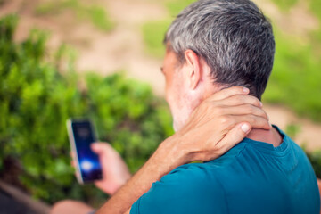 Neck pain using smartphone outdoor. Healthcare, lifestyle and technology concept