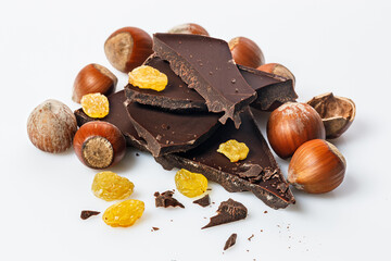 Nuts, sweet raisins and and stack of a dark chocolate on a white background. Ripe wild hazelnuts and bitter chocolate. Natural organic products. Copy space. Food still life